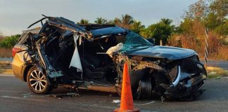 A mangled Ford SUV on a highway parked next to an orange highway cone