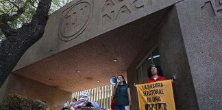Mexican activists standing with a pile of plastic election campaign banners and posters in front of Mexico's National Action Party headquarters in Mexico City