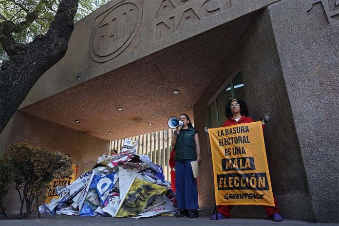 Mexican activists standing with a pile of plastic election campaign banners and posters in front of Mexico's National Action Party headquarters in Mexico City