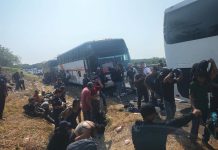 Migrants on the side of the road by buses