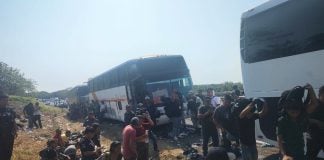 Migrants on the side of the road by buses
