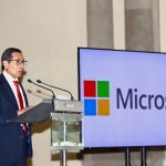 Mexico Finance Minister Rogelio Ramirez de la O standing at a podium beside a large monitor that bears the name and logo of Microsoft