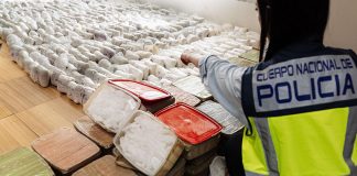Police officer pointing at hundreds of methamphetamine parcels in clear plastic wrap confiscated in a Sinaloa Cartel meth bust in Spain