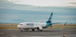 WestJet plane on a runway with a worker guiding the plane from outside