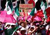 Anti-AMLO protesters wearing pink and waving Mexican flags crowd together with a sign saying "sin miedo, todos a votar," and bearing Xóchitl Gálvez's logo.
