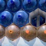 Empty 20-gallon plastic jugs of water arranged in a pile, pyramid style