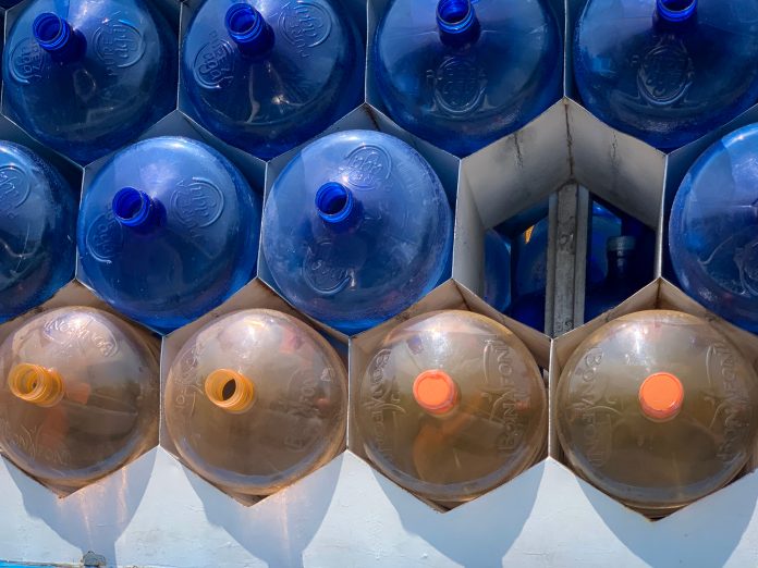 Empty 20-gallon plastic jugs of water arranged in a pile, pyramid style