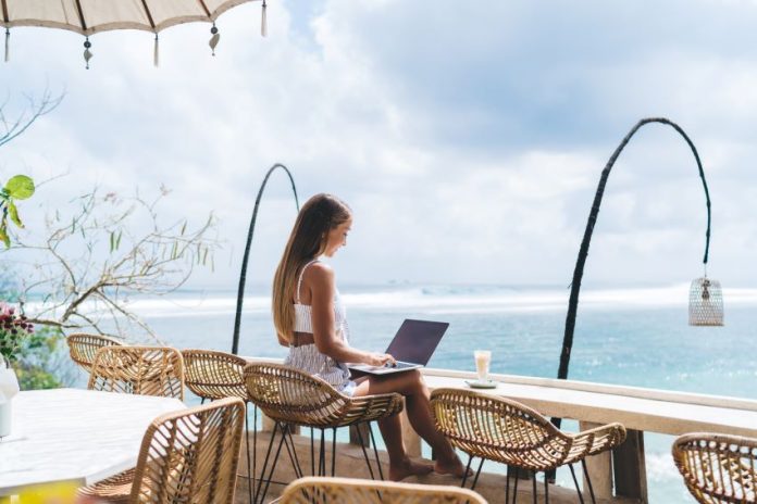 girl working from the beach as a digital nomad
