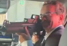 Former U.K. ambassador to Mexico Jonathan Benjamin points an assault rifle at the camera in a blurry video screenshot