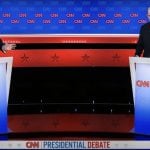 U.S. President Biden and Trump debate issues like immigration, border security and more from behind podiums on a stage.