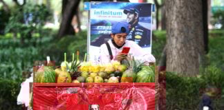 Young fruit seller looks at his cell phone in Mexico City