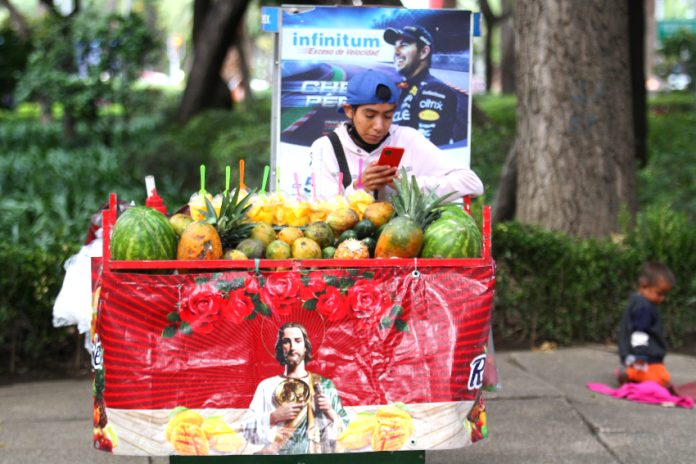 Young fruit seller looks at his cell phone in Mexico City