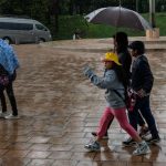 A family walks in the rain under an umbrella during a storm in Mexico City