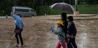 A family walks in the rain under an umbrella during a storm in Mexico City