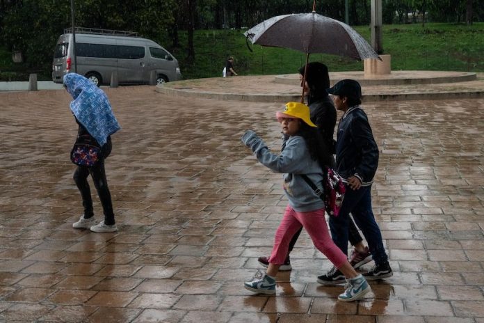 A family walks in the rain under an umbrella during a storm in Mexico City