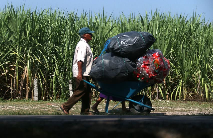 A man with a wheelbarrow of plastic bottles