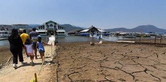 Family walking toward a marina in the Miguel Aleman reservoir in Mexico state. The lake bed they are walking on is cracked mud with no water.