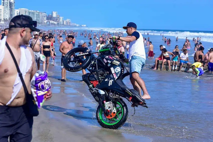A man rides a Yamaha bike on a crowded beach in Acapulco