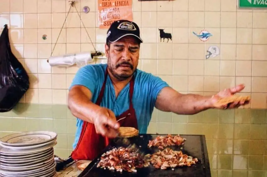 Mexican man preparing tacos de carnitas