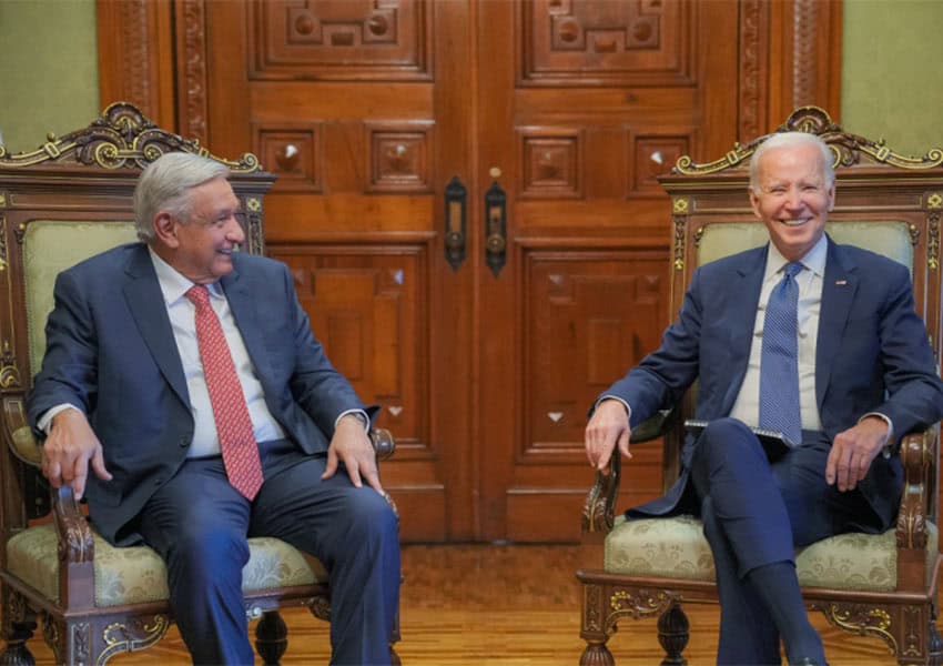 President of Mexico Andres Manuel Lopez Obrador and U.S. President Joe Biden sitting side by side in a formal room in the National Palace. Both are smiling.