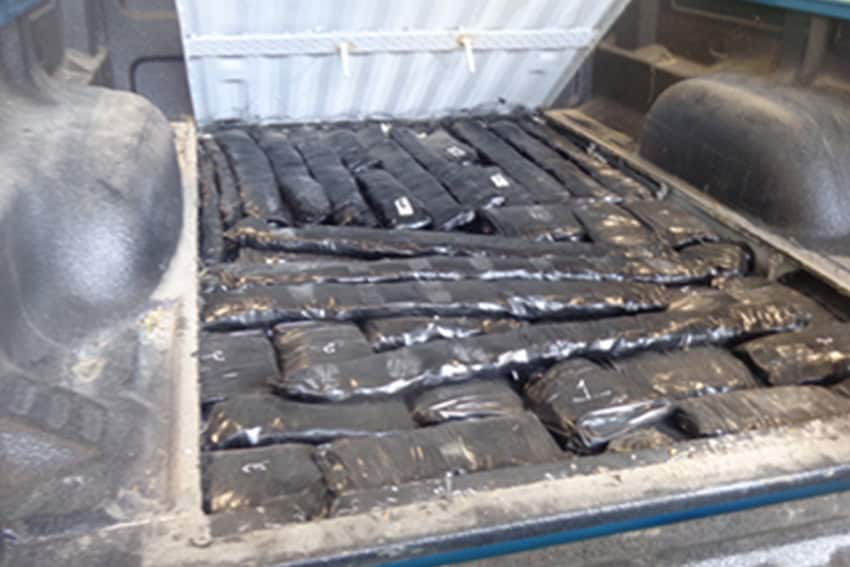 Truck bed with secret compartment opened revealing dozens of packets of methamphetamine