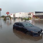 Car with water nearly up to its wheel well in severe flooding on a street in Merida, Yucatan