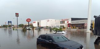 Car with water nearly up to its wheel well in severe flooding on a street in Merida, Yucatan