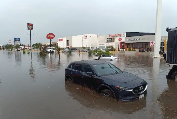 Car with water nearly up to its wheel well in severe flooding on a street in Merida, Yucatan