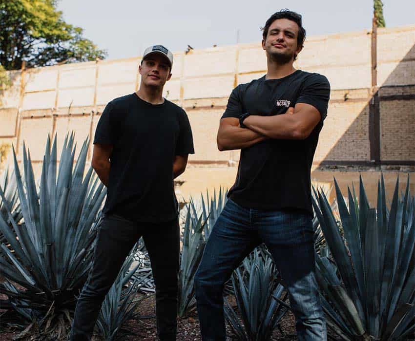 The makers of Tesla Mezcal, Michael Arbanas and Carlos Soto, posing among agave plants
