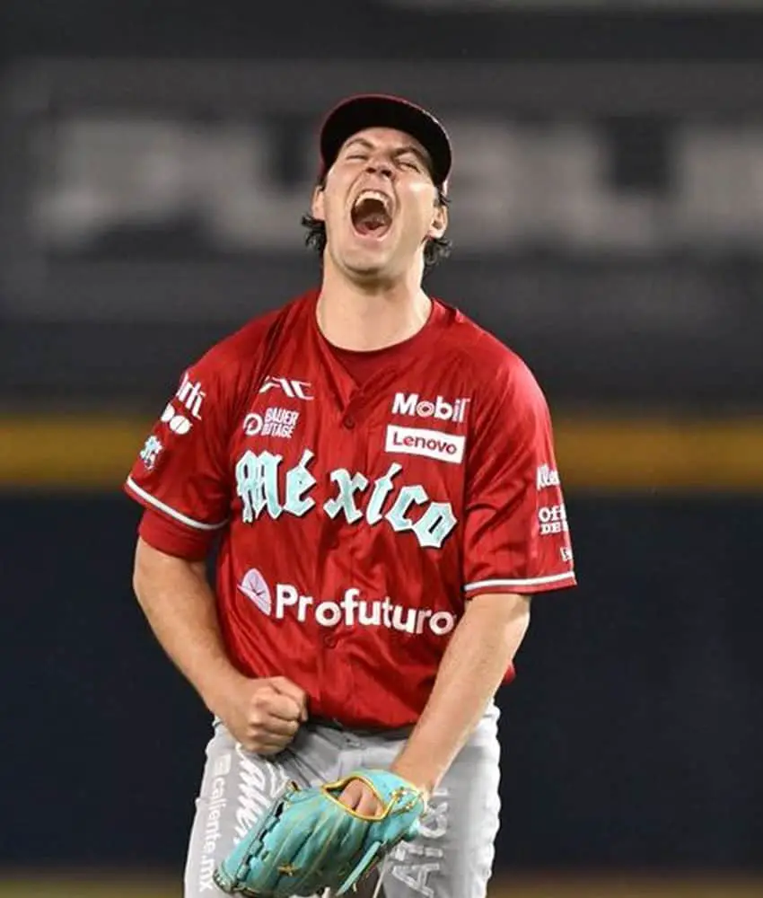 Mexican Baseball League pitcher Trevor Bauer after setting a strikeout record shouts with excitement on the mound. His hand not holding his glove is in a fist