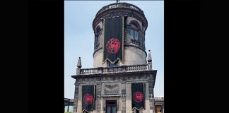 Part of Chapultepec Castle with what looks like three black and red banners hanging from it
