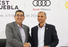 Puebla Governor Sergio Salomon and Audi Mexico President Tarek Mashour shaking hands in front of a temporary wall with the Audi logo.