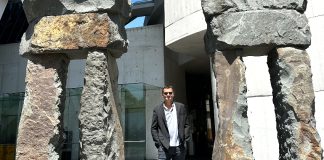 Travis Bembenek standing next to giant stone statues