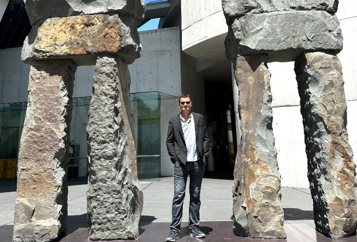 Travis Bembenek standing next to giant stone statues
