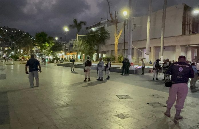 Police and security forces patrol a public square in Acapulco at night.
