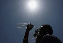 A person pours water on his face under blazing sun