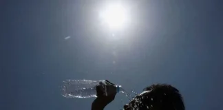A person pours water on his face under blazing sun