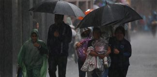 People shelter from the rain under umbrellas and ponchos in Mexico City