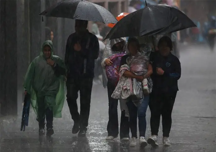 People shelter from the rain under umbrellas and ponchos in Mexico City