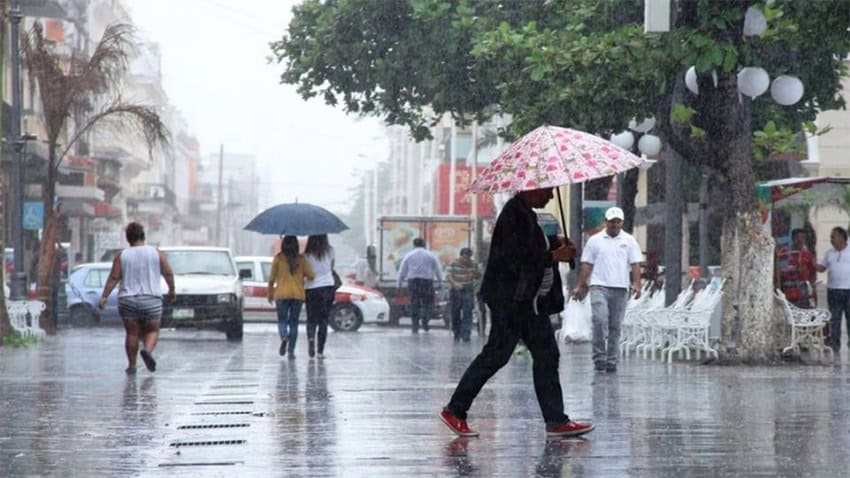People walk holding umbrellas in the rain in a Mexican city