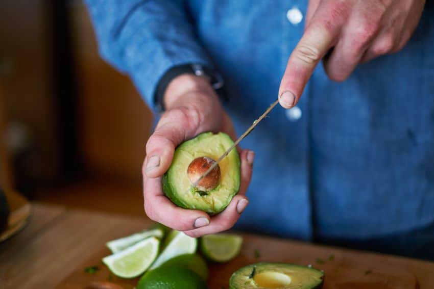 A man opening an avocado with a knife