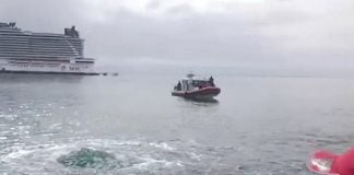 A fisherman points out the bubbling "water eye" in the ocean off Cozumel Island, with a cruise ship and another fishing boat in the background.