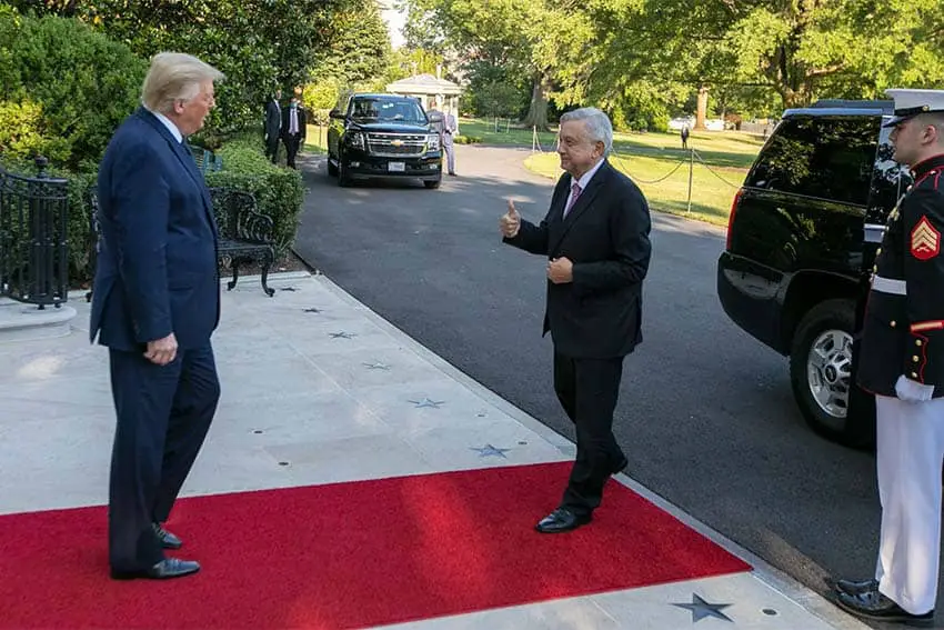 Mexico's president Lopez Obrador exiting a limo and stepping on a red carpet at the White House, heading toward then U.S. President Donald Trump in 2020.