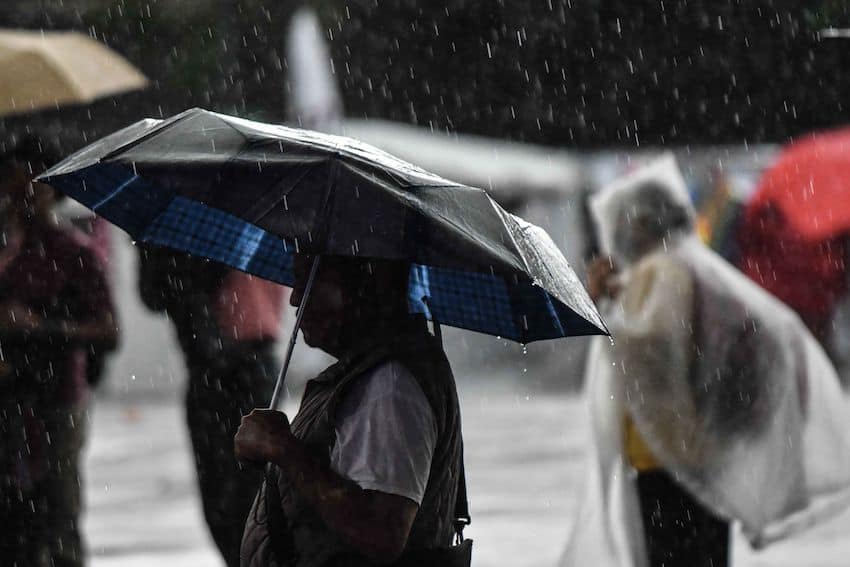 A person holds an umbrella in the rain