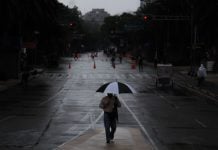 A person walks holding an umbrella in the rain
