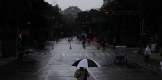 A person walks holding an umbrella in the rain