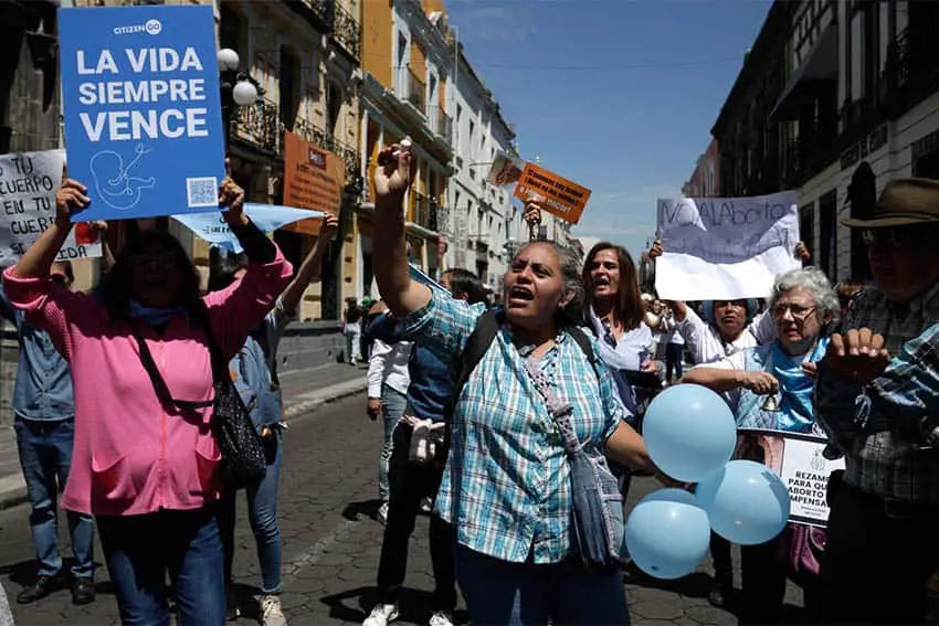 Anti-abortion activists in Puebla, Mexico, carrying signs in Spanish and marching through the streets ahead of a vote to decriminalize abortion in the state.