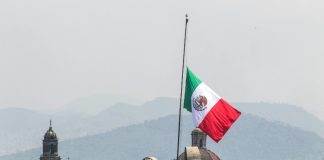 A Mexican flag waves in front of churches in Mexico City
