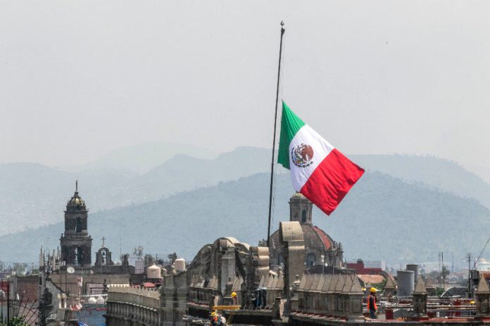 A Mexican flag waves in front of churches in Mexico City