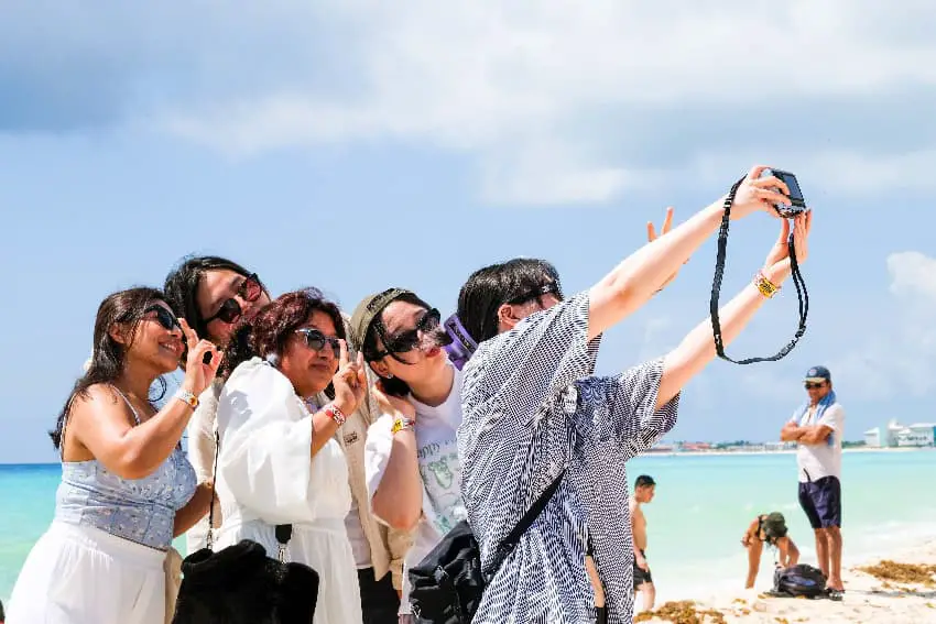 Tourists take a selfie on a beach in Cancún